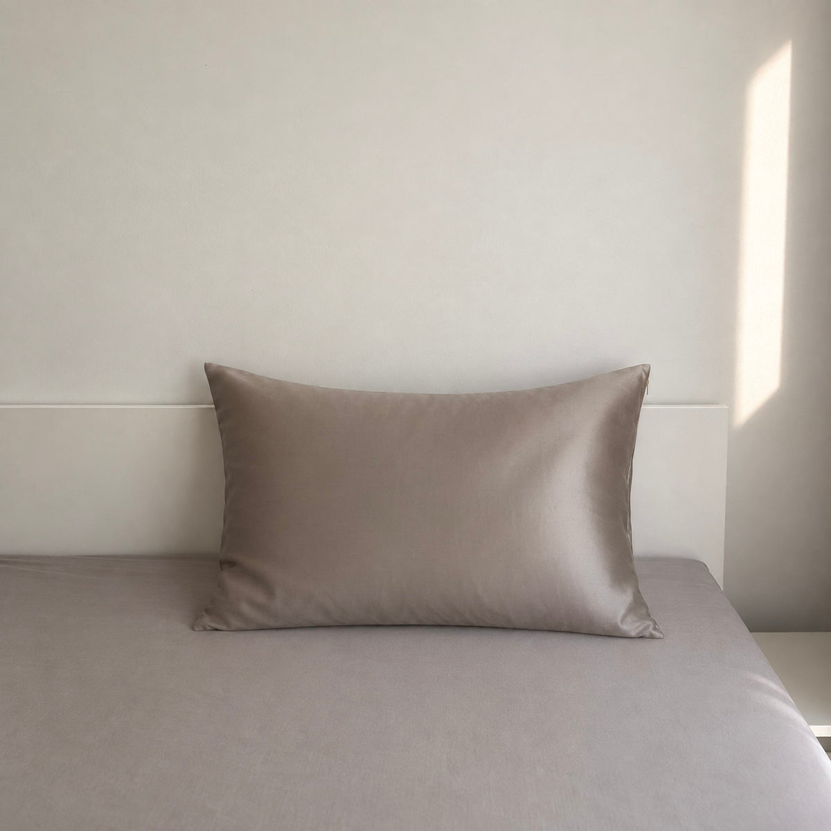 Jedwabna poszewka Lumière 22 momme w kolorze taupe na łóżku